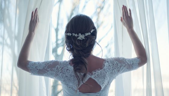kobieta w sukni ślubnej stojąca przy oknie
