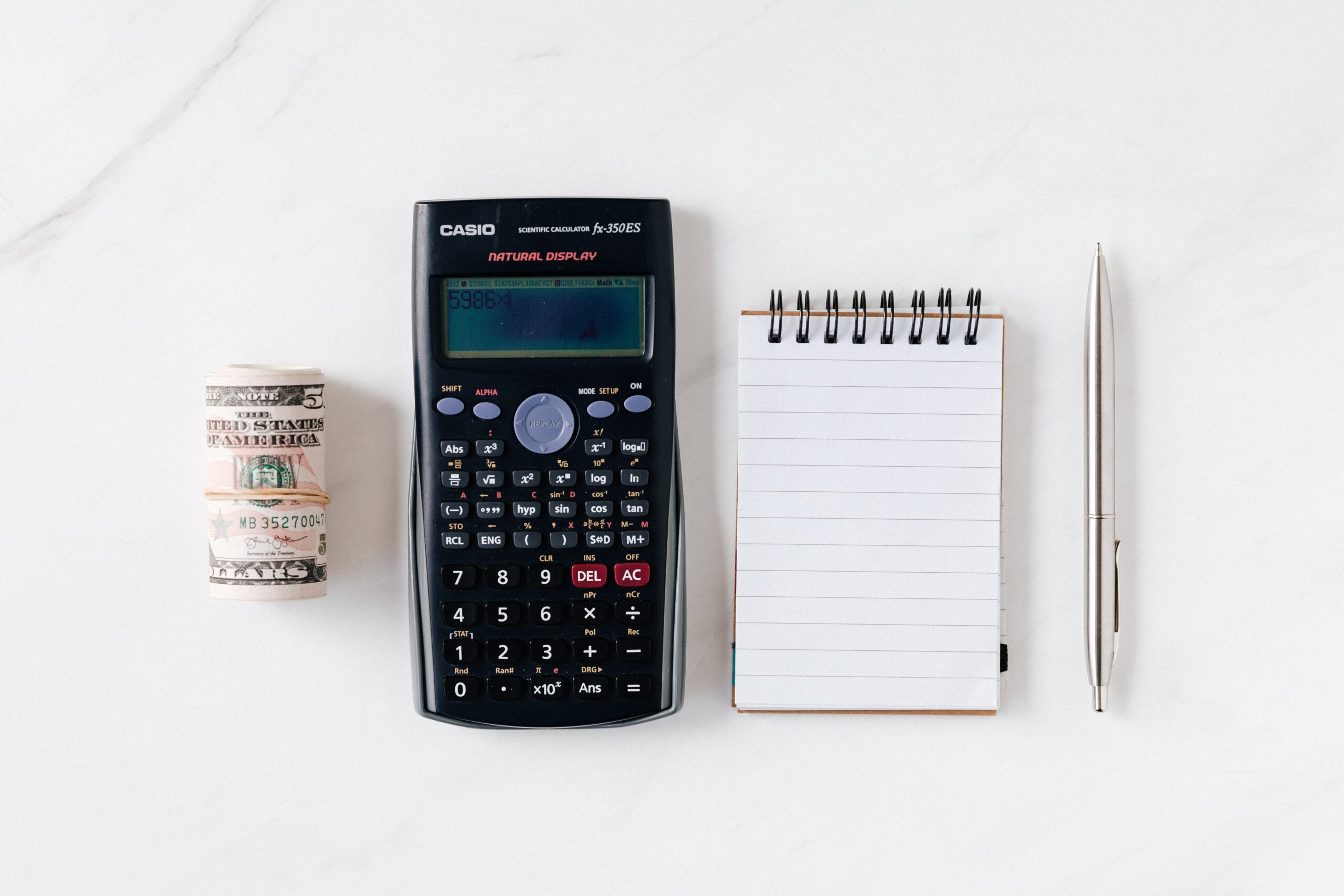 Długopis, notatnik, kalkulator i plik pieniędzy na białym tle